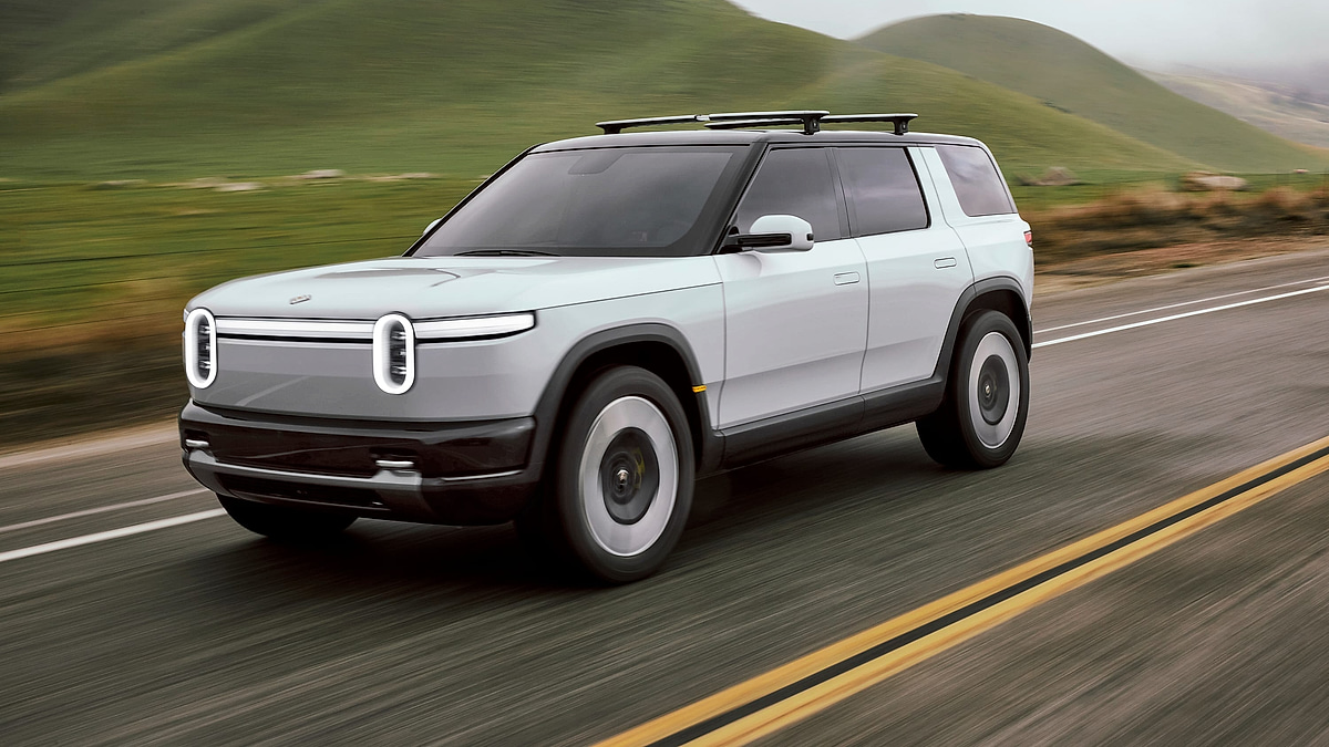 Rivian R2S electric SUV driving on a highway with rolling hills in the background
